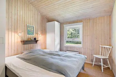 a bedroom with a bed and a chair and a window at BL1293-Saltum-Havmandens-Vej-24 in Saltum