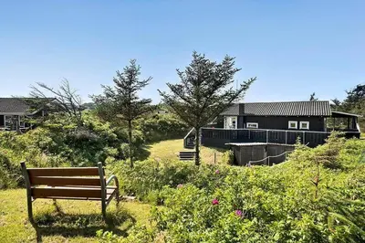 a bench sitting in the grass in front of a house at BL1100-Blokhus-Klitvejen-44 in Blokhus