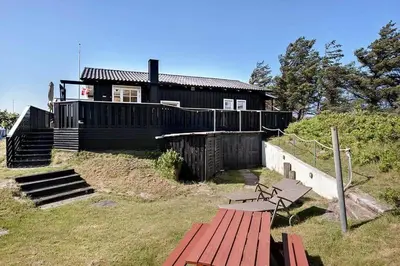 a house on a hill with a bench in front of it at BL1100-Blokhus-Klitvejen-44 in Blokhus