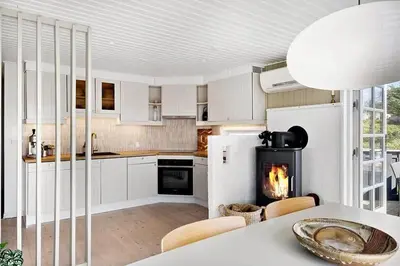 a kitchen with a table and a fireplace in it at BL1100-Blokhus-Klitvejen-44 in Blokhus