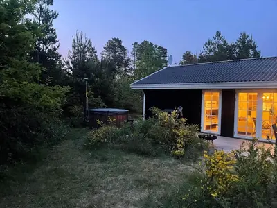 a small black house with a deck in a yard at BL1109-Blokhus-Bag-Hojen-78 in Blokhus