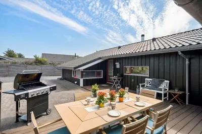 a patio with a table and a grill on a deck at BL1102-Blokhus-Solbakkevej-17 in Blokhus