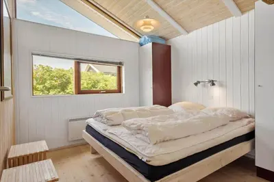 a large bed in a room with a window at BL1102-Blokhus-Solbakkevej-17 in Blokhus