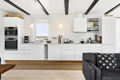 a kitchen with white cabinets and a gray chair at BL1310-Blokhus-Moreavej-33-A in Blokhus