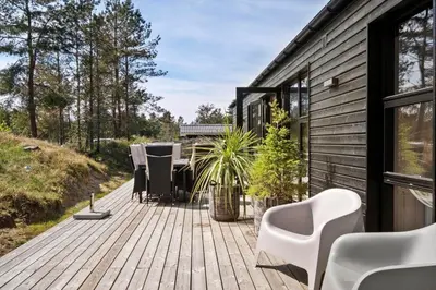 a wooden deck with chairs and tables on a house at BL1765-Blokhus-Plantagevej-2B in Blokhus