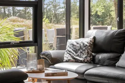 a living room with a leather couch and a table at BL1765-Blokhus-Plantagevej-2B in Blokhus