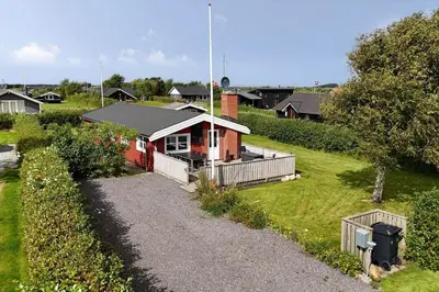 a small red house on a hill with a yard at G151-Lemvig-Porsevej-51 in Lemvig