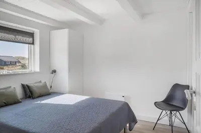 a bedroom with a bed and a chair and a window at 258-Harboore-Merchantvej-5 in Harboør