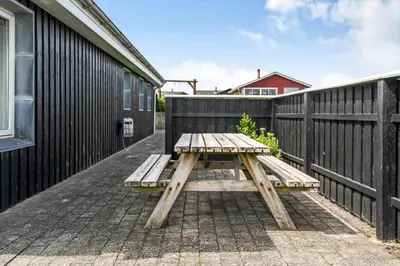 a wooden picnic table on a patio next to a fence at G430-Lemvig-Myntevej-30 in Lemvig