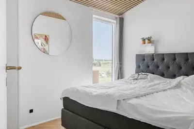 a bedroom with a large bed and a mirror at 265-Harboore-Lucievej-6-b in Harboør
