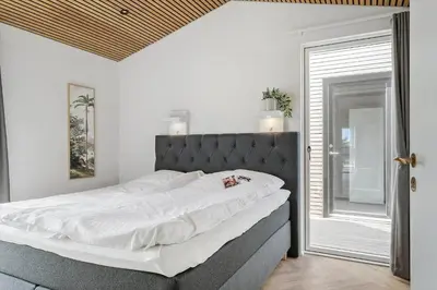 a bedroom with a large bed with white sheets at 265-Harboore-Lucievej-6-b in Harboør