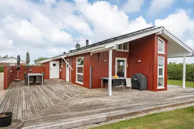 a red house with a large wooden deck at 600-Lemvig-Porsevej-115 in Lemvig