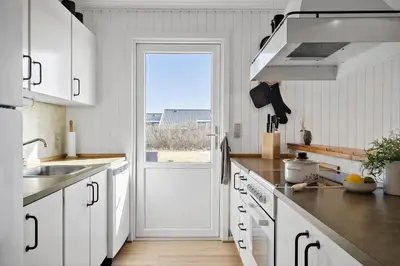 a kitchen with white cabinets and a large door at 157-Harboore-Vejlby-Klit-65 in Harboør