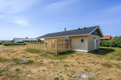 a small house with a fence in a yard at 123-Harboore-Vejlby-Klit-83 in Harboør