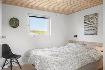 a bedroom with a bed and a chair and a window at G245-Lemvig-Porsevej-45 in Lemvig