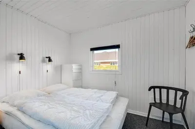 a white bedroom with a bed and a chair at 235-Harboore-Vejlby-Klit-139 in Harboør