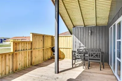 a wooden deck with a table and a fence at 235-Harboore-Vejlby-Klit-139 in Harboør
