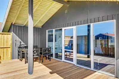 an open deck with a dining table and glass doors at 235-Harboore-Vejlby-Klit-139 in Harboør