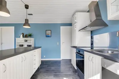 a kitchen with white cabinets and blue walls at 235-Harboore-Vejlby-Klit-139 in Harboør