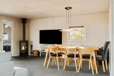 a dining room with a table and chairs and a television at 153-Harboore-Vejlby-Klit-77 in Harboør