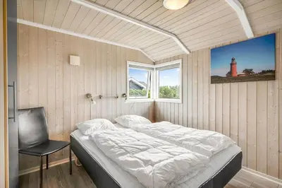 a bedroom with a bed and a chair and a lighthouse at 234-Harboore-Neerlandiavej-21 in Harboør