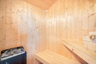 a wooden sauna with a bench and a basket at 234-Harboore-Neerlandiavej-21 in Harboør