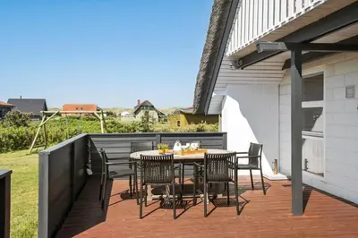 a patio with a table and chairs on a deck at 300-Harboore-Fourmivej-29 in Harboør