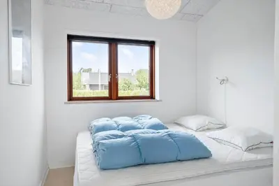 a white room with a bed with blue pillows on it at G161-Lemvig-Porsevej-61 in Lemvig
