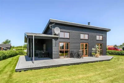 a black house with a deck and a yard at G161-Lemvig-Porsevej-61 in Lemvig