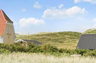 a church with hills in the background and a house at 225-Harboore-Neerlandiavej-268 in Harboør