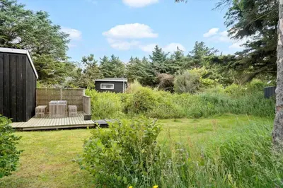 a garden with a wooden deck and a cabin at 202-Harboore-Viktoriavej-12-a in Harboør
