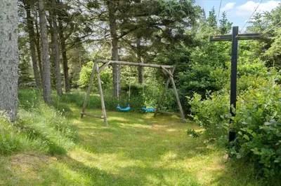 an empty swing set in a yard with trees at 202-Harboore-Viktoriavej-12-a in Harboør
