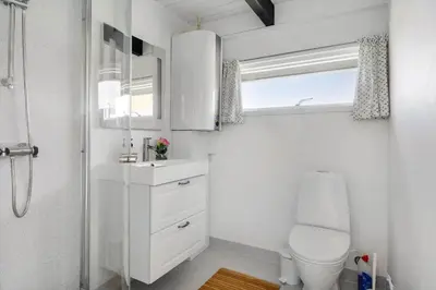 a bathroom with a toilet and a sink and a window at 301-Harboore-Themisvej-11 in Harboør