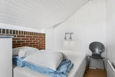 a white room with a bed and a chair at G149-Lemvig-Porsevej-49 in Lemvig