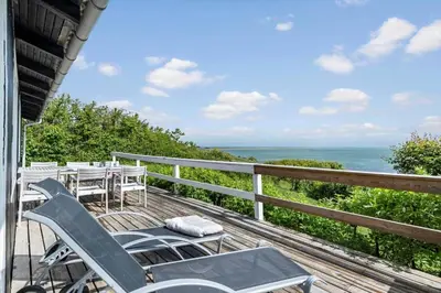 a deck with chairs and tables and the ocean at G398-Lemvig-Violvej-98 in Lemvig