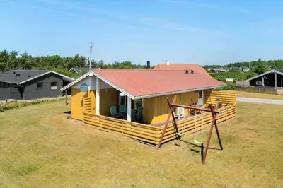 a small house with a red roof in a field at 154-Harboore-Vejlby-Klit-103 in Harboør