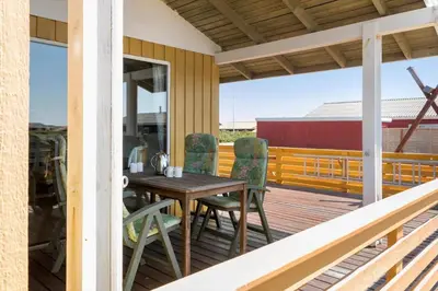 a wooden table and chairs on a deck at 154-Harboore-Vejlby-Klit-103 in Harboør