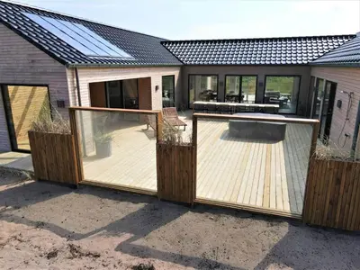 a wooden deck with a grill and a house at 350-Harboore-Alkajavej-13-A in Harboør