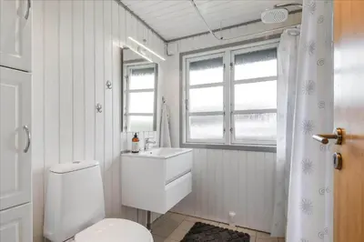 a bathroom with a toilet and a sink and a window at 251-Harboore-Neerlandiavej-230 in Harboør