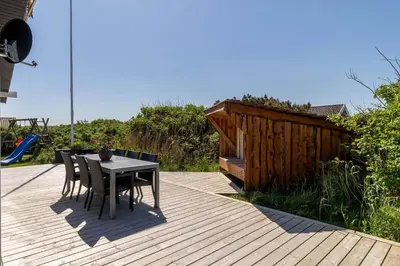a patio with a table and chairs on a deck at 251-Harboore-Neerlandiavej-230 in Harboør