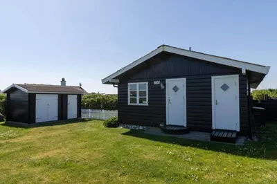 a small cabin with white doors on a yard at 251-Harboore-Neerlandiavej-230 in Harboør