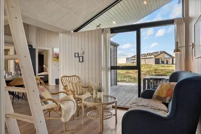 a living room with a staircase and a table and chairs at 332-Harboore-Hvilehjemsvej-20 in Harboør