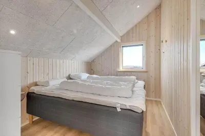 a large bed in a room with wooden walls at 257-Harboore-Dalevej-8 in Harboør