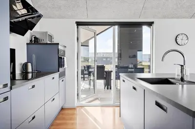 a kitchen with white cabinets and a large glass door at 360-Harboore-Alkajavej-11 in Harboør