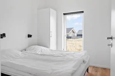 a bed in a white room with a window at 360-Harboore-Alkajavej-11 in Harboør