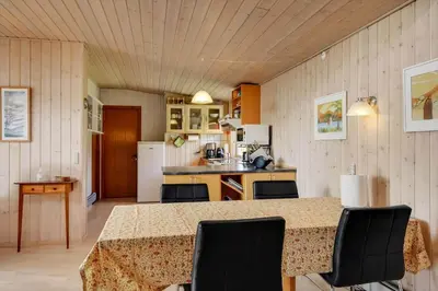 a kitchen with a table with chairs and a refrigerator at G129-Lemvig-Gjelleroddevej-129 in Lemvig