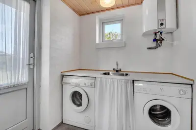 a laundry room with a washing machine and a sink at G129-Lemvig-Gjelleroddevej-129 in Lemvig