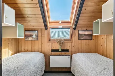 two beds in a room with wooden walls and a window at 127-Harboore-Vejlby-Klit-237 in Harboør