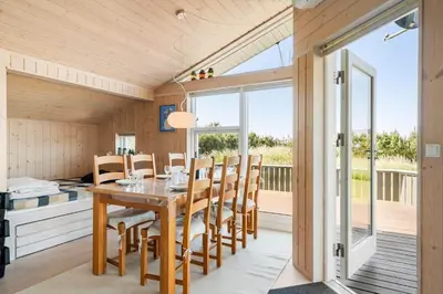 a dining room with a table and chairs and a balcony at 104-Harboore-Neerlandiavej-29 in Harboør