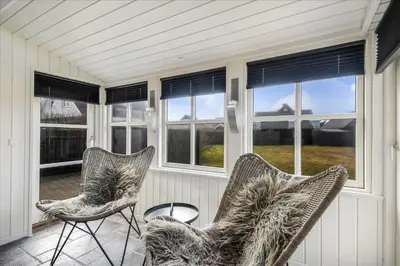 a screened in porch with two chairs and windows at 715-Thyboron-Limfjordsvej-17-a in Thyborøn